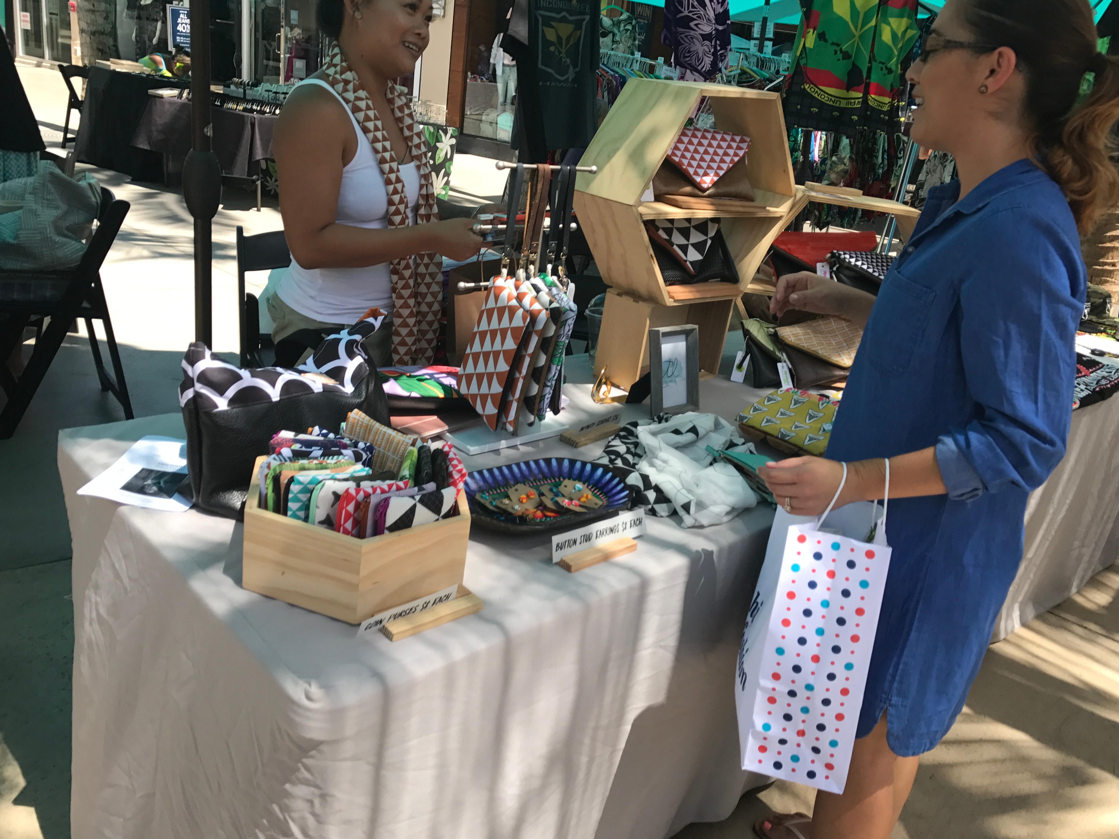 Vendor selling patterned textiles and coin purses at market stall