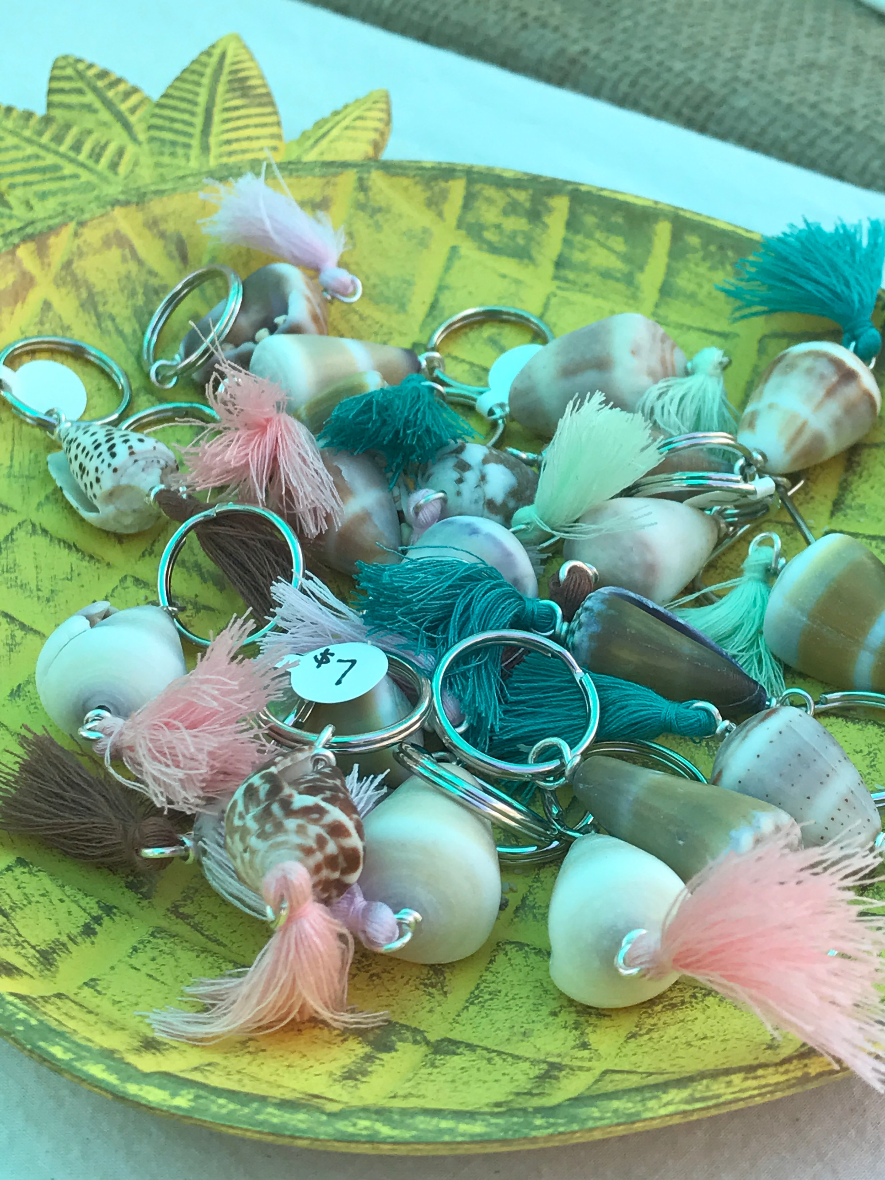 Shell keychains with pink and teal tassels on decorative plate