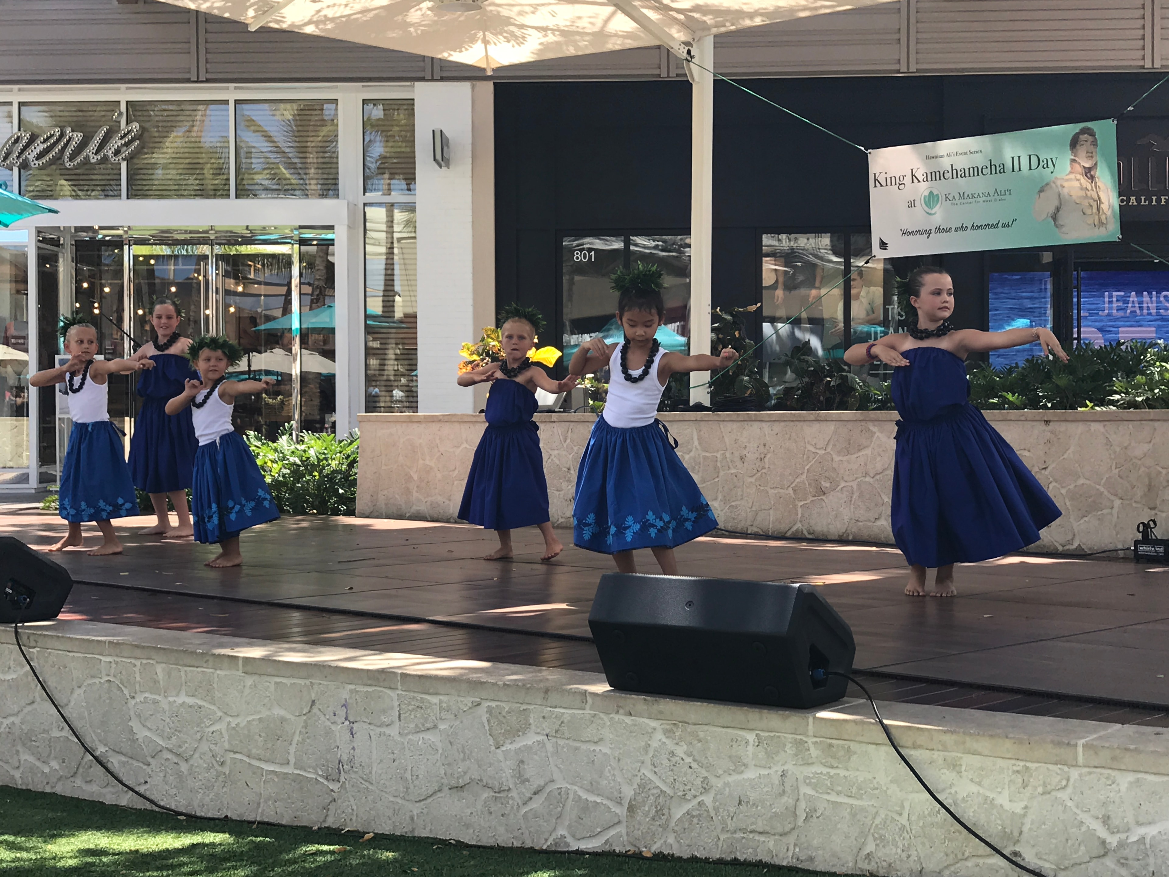 Children performing traditional hula dance on outdoor stage