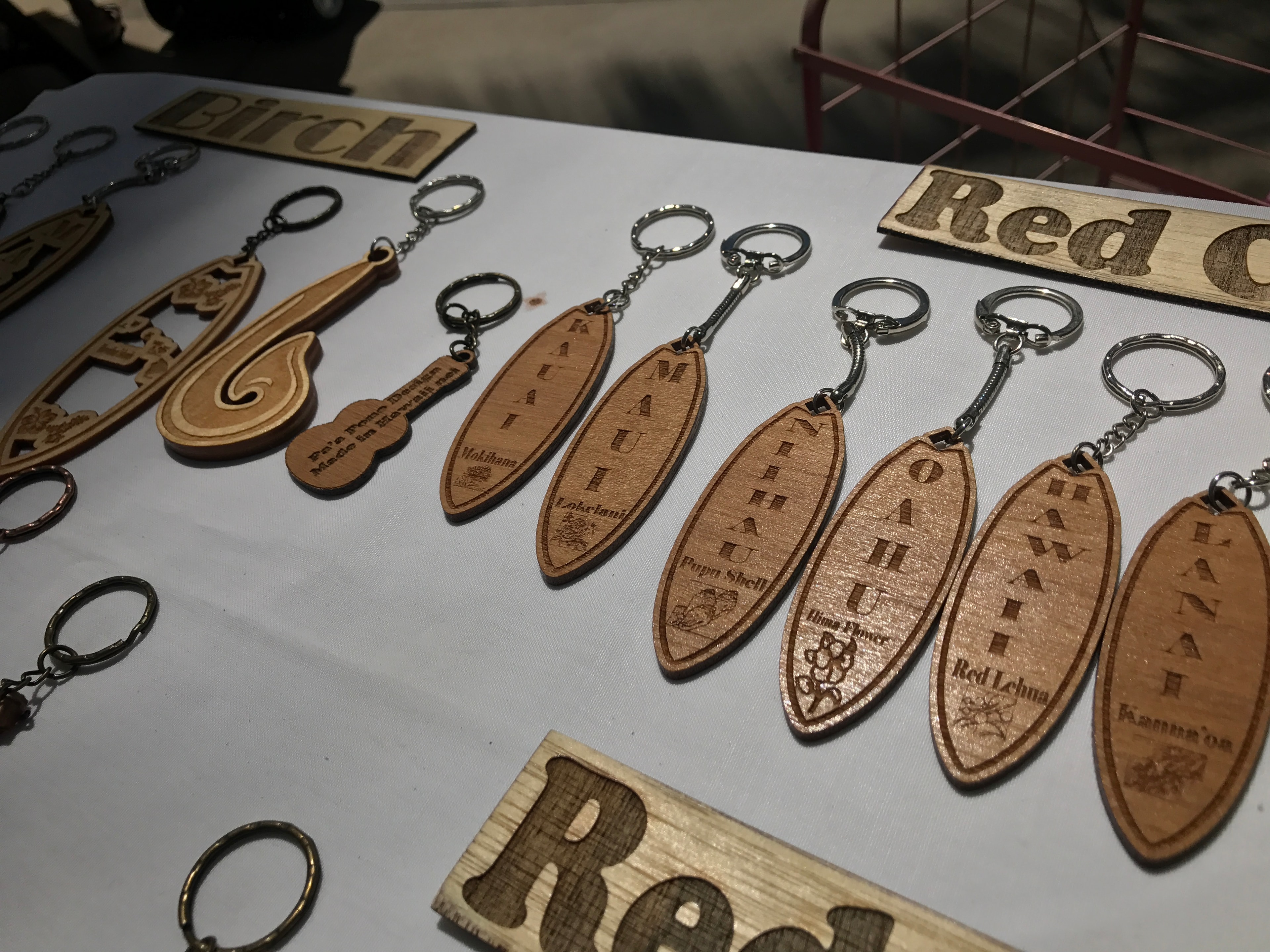 Wooden island-name surfboard keychains — Kauai, Maui, Niihau, Oahu, Hawaii — on display table
