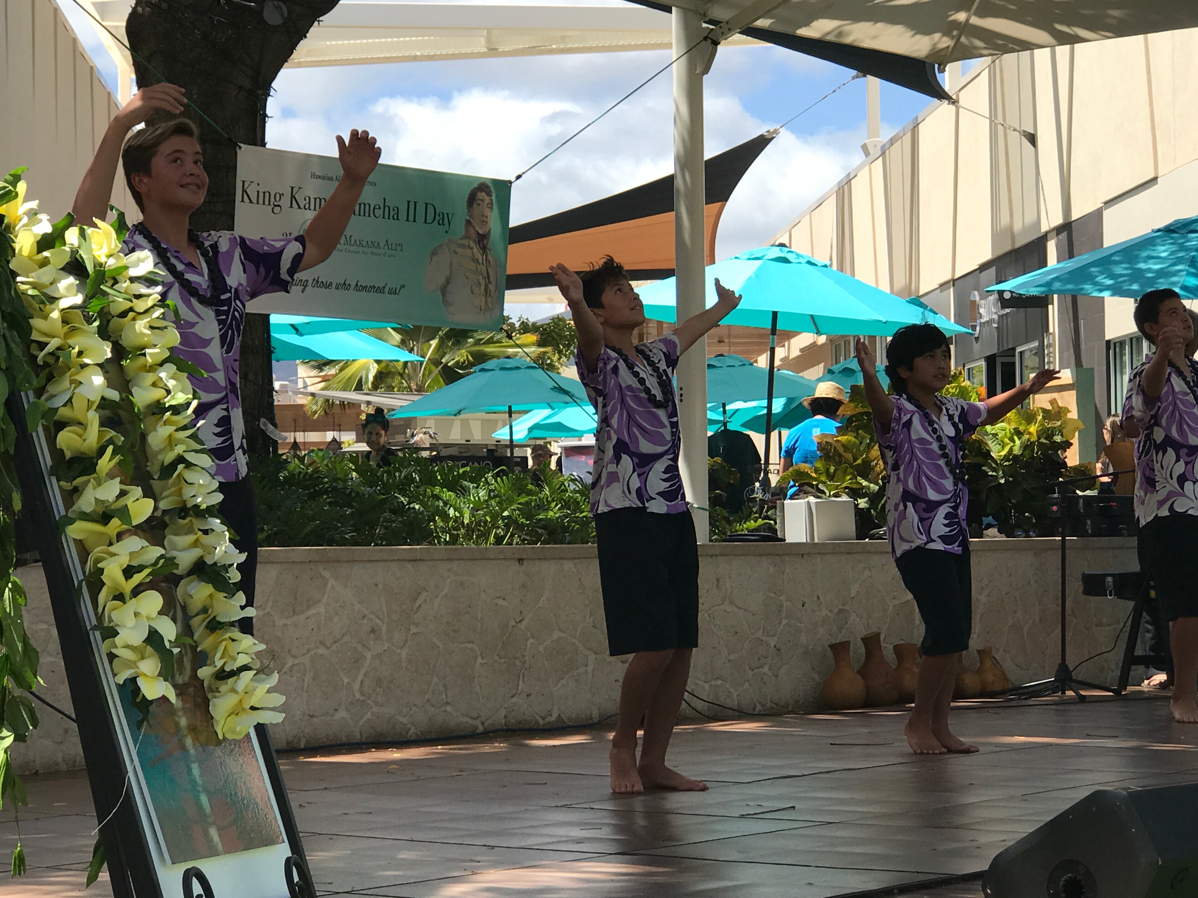 Young male hula dancers in purple and white performing at King Kamehameha II Day stage