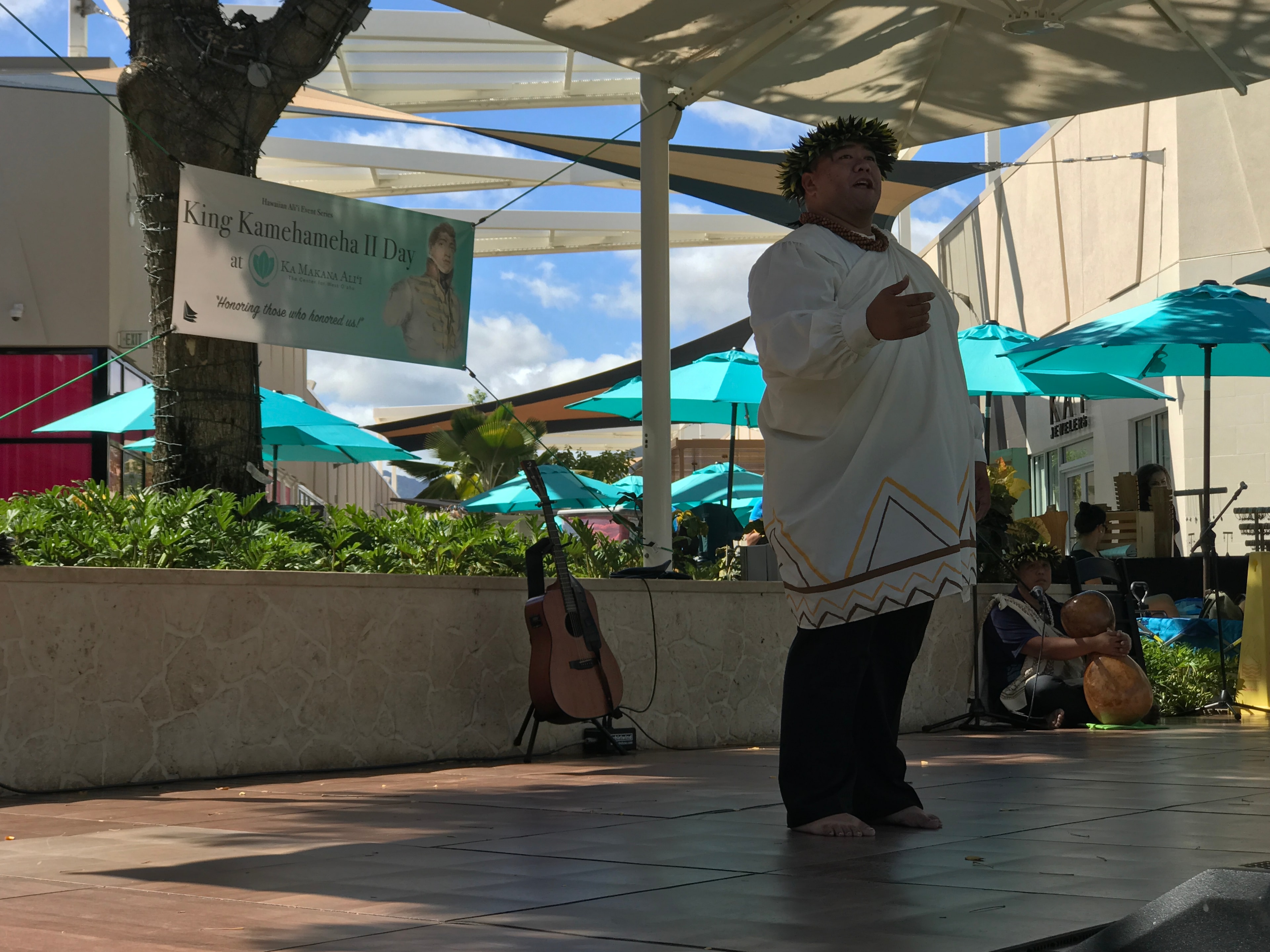 Male hula dancer in white kapa costume performing at King Kamehameha II Day outdoor stage