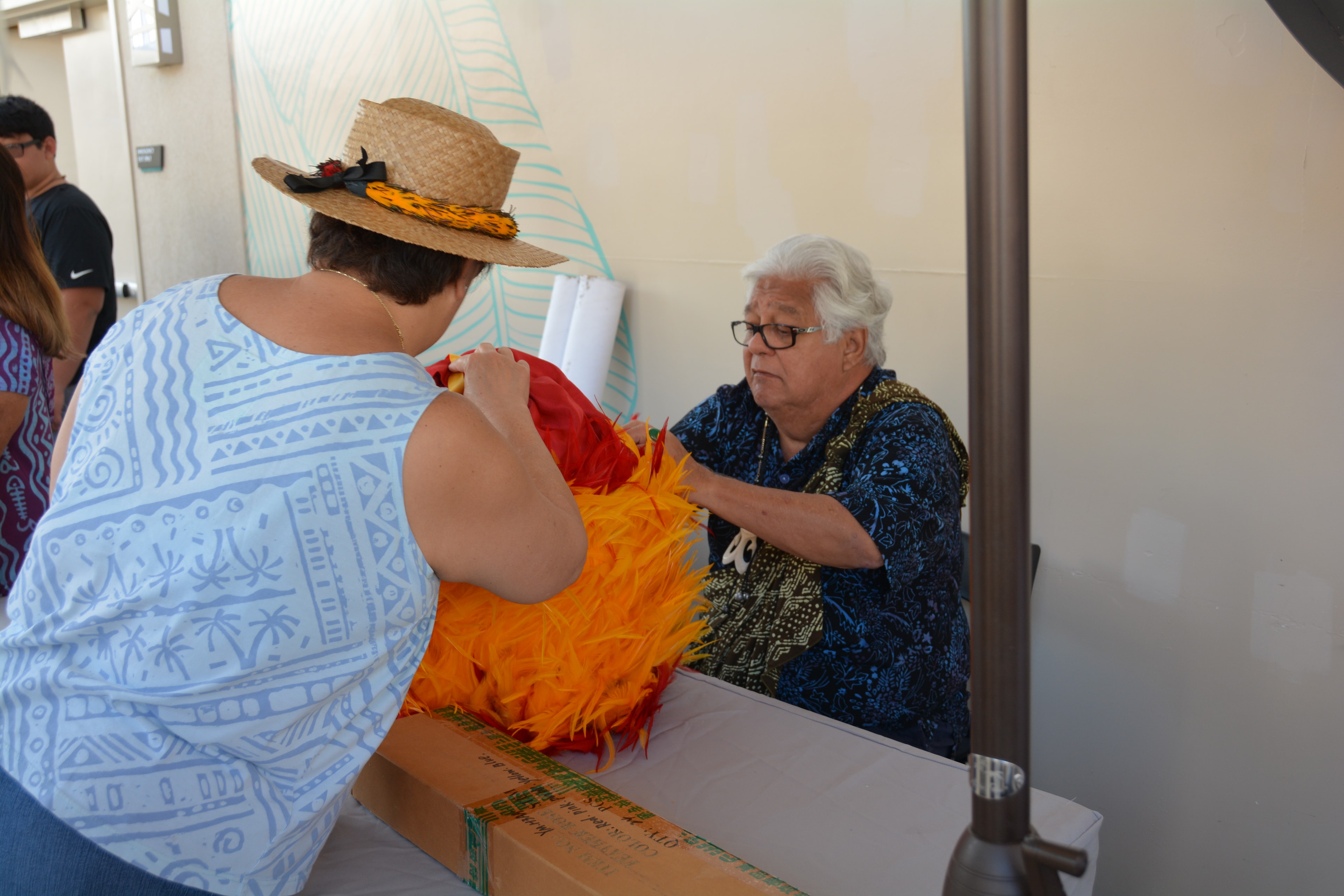 Woman in straw hat showing elder colorful lei