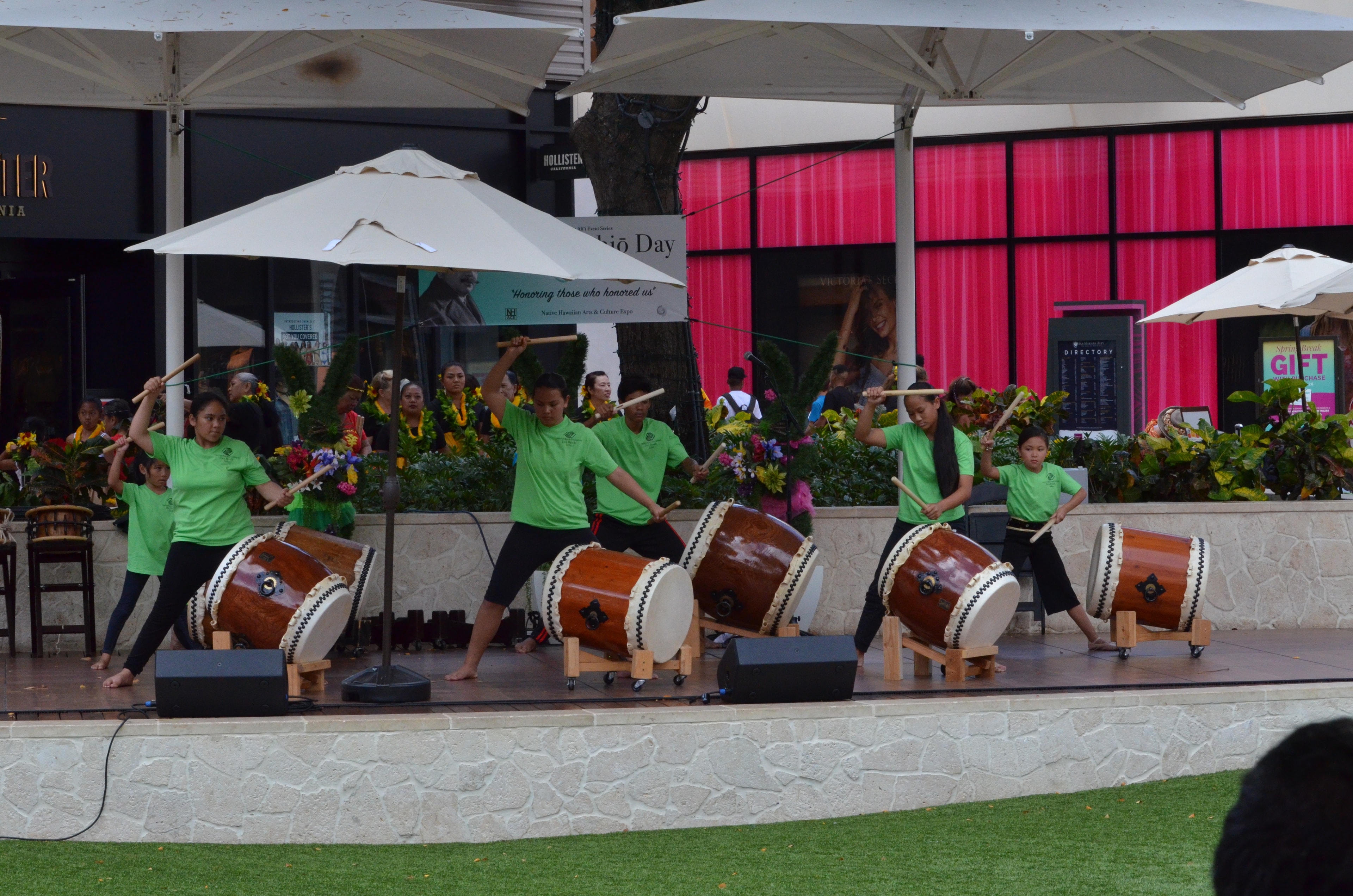 Performers in green shirts playing taiko drums