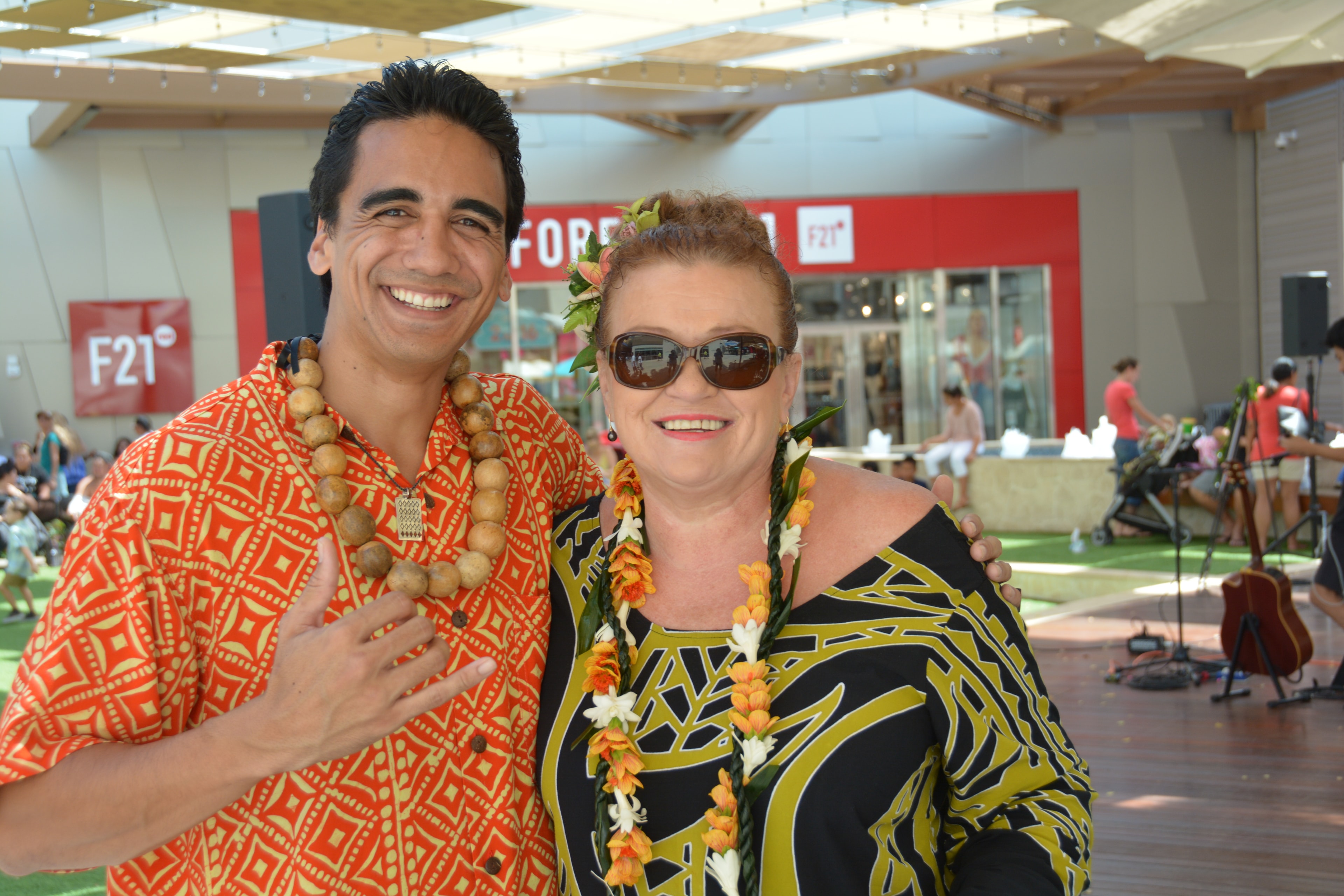 Two people wearing lei and Hawaiian attire at Prince Kūhiō Day event