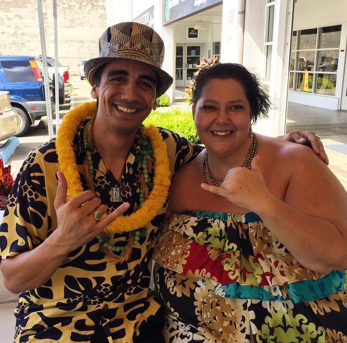 Two people in tropical Hawaiian costumes smiling