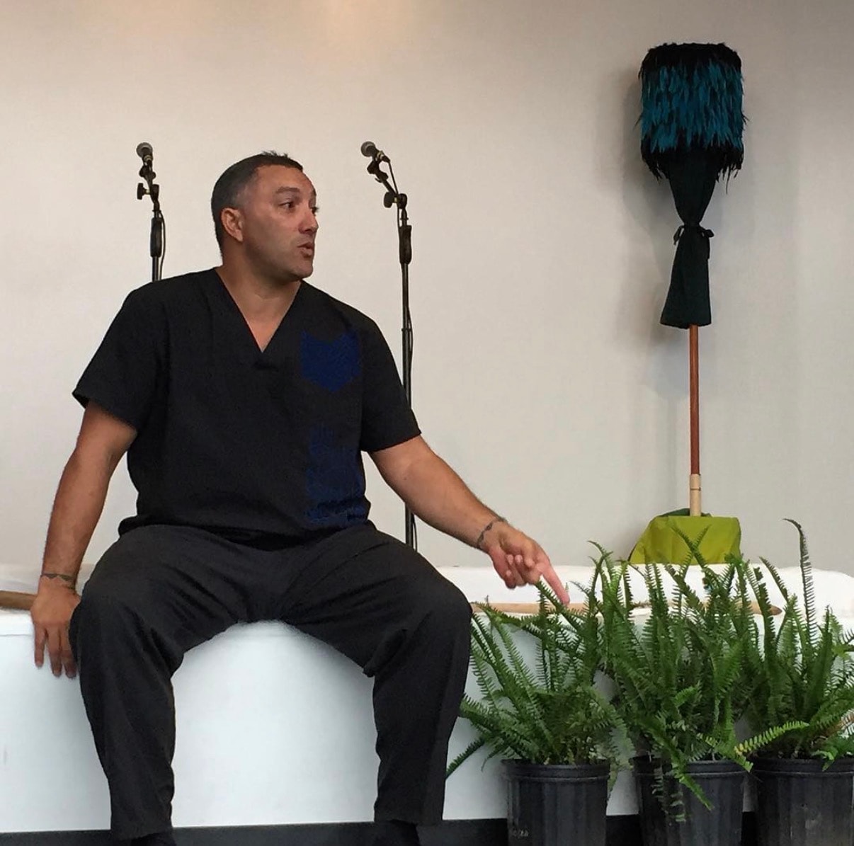 Man speaking at microphones with plants