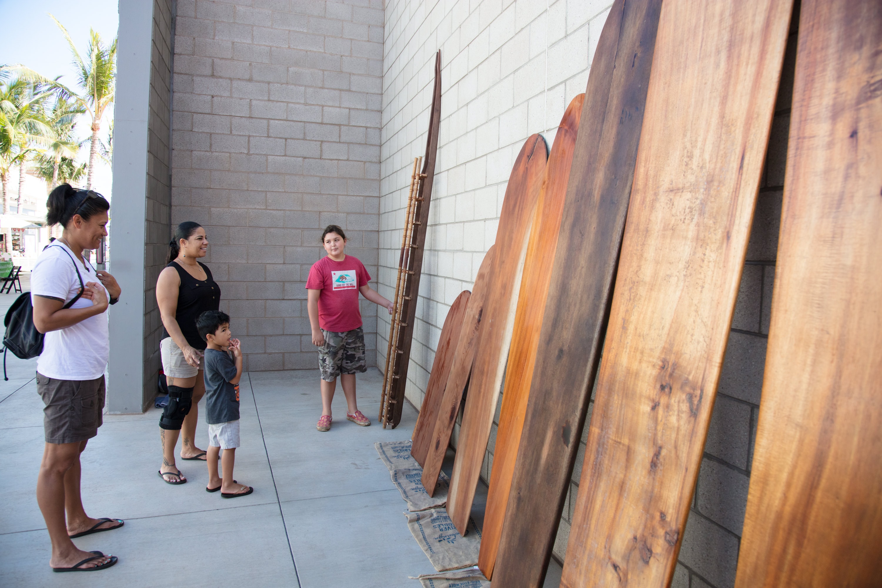 Family viewing wooden surfboards museum exhibit