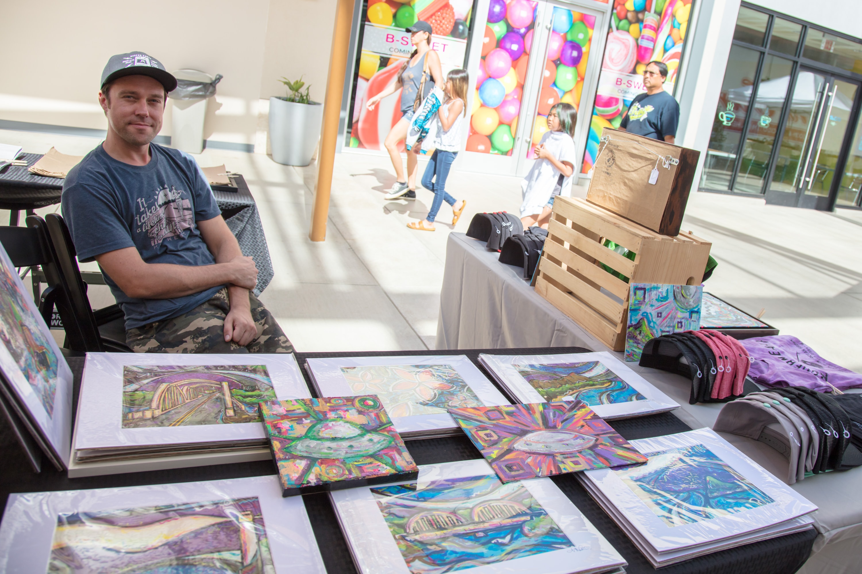 Artist displaying colorful artwork at market booth