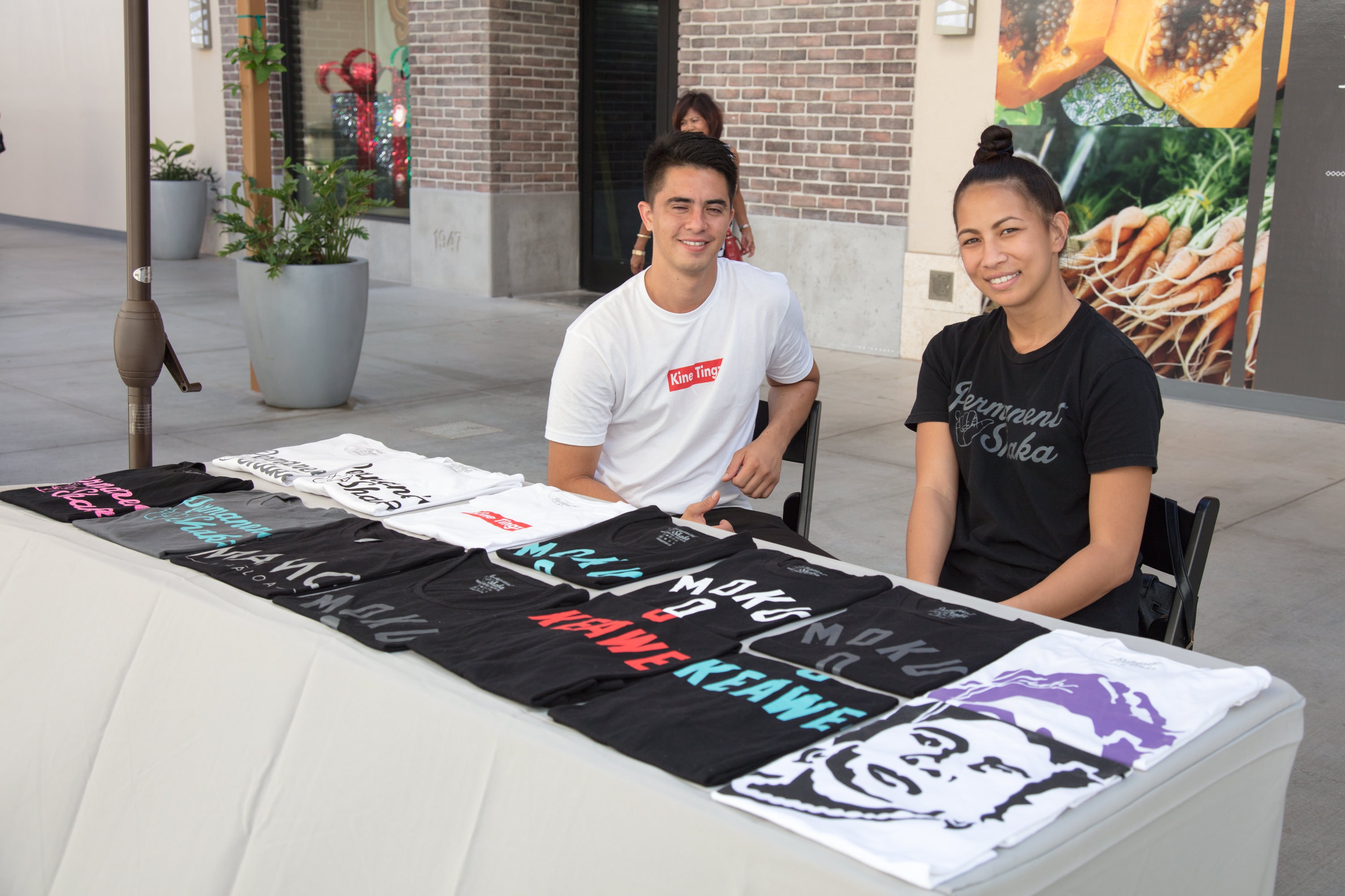 Two people selling graphic t-shirts outdoors