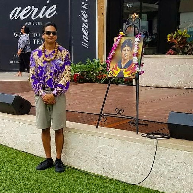 Man in purple shirt standing near portrait display